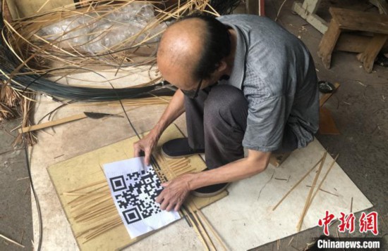 谢世仰将竹篾有序地摆在地上,对照着打印出来的二维码开始编织。 彭莉芳 摄
